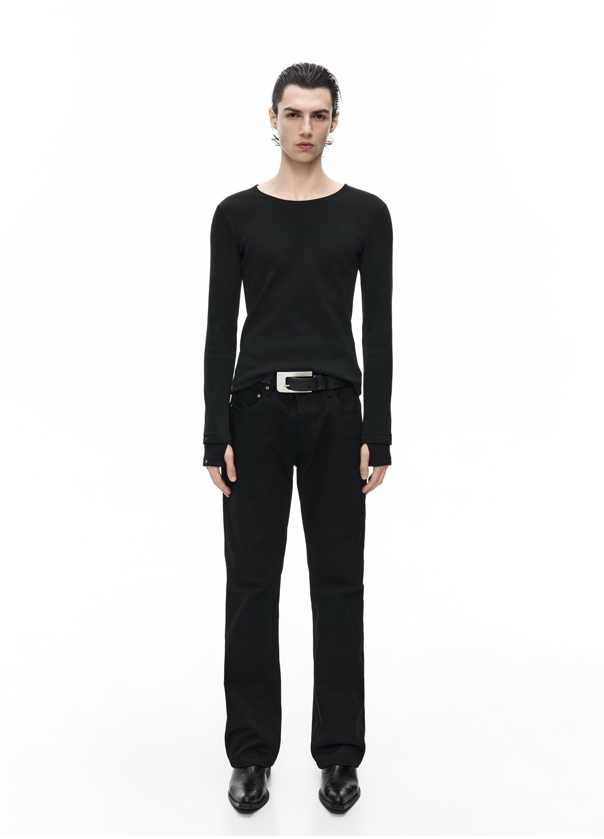 Front view of a model in a fitted black long-sleeve top with a round neckline and extended cuffs, worn with black trousers.