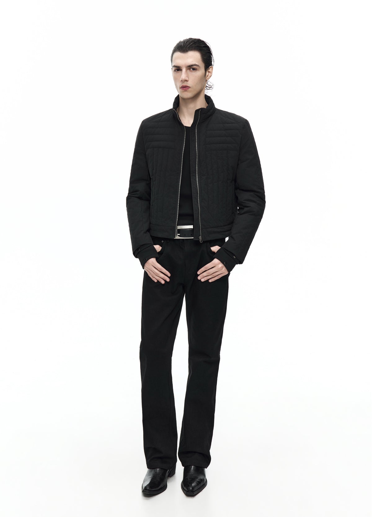 Front view of a model in a short black quilted jacket worn open, showing horizontal chest channels and a stand collar.
