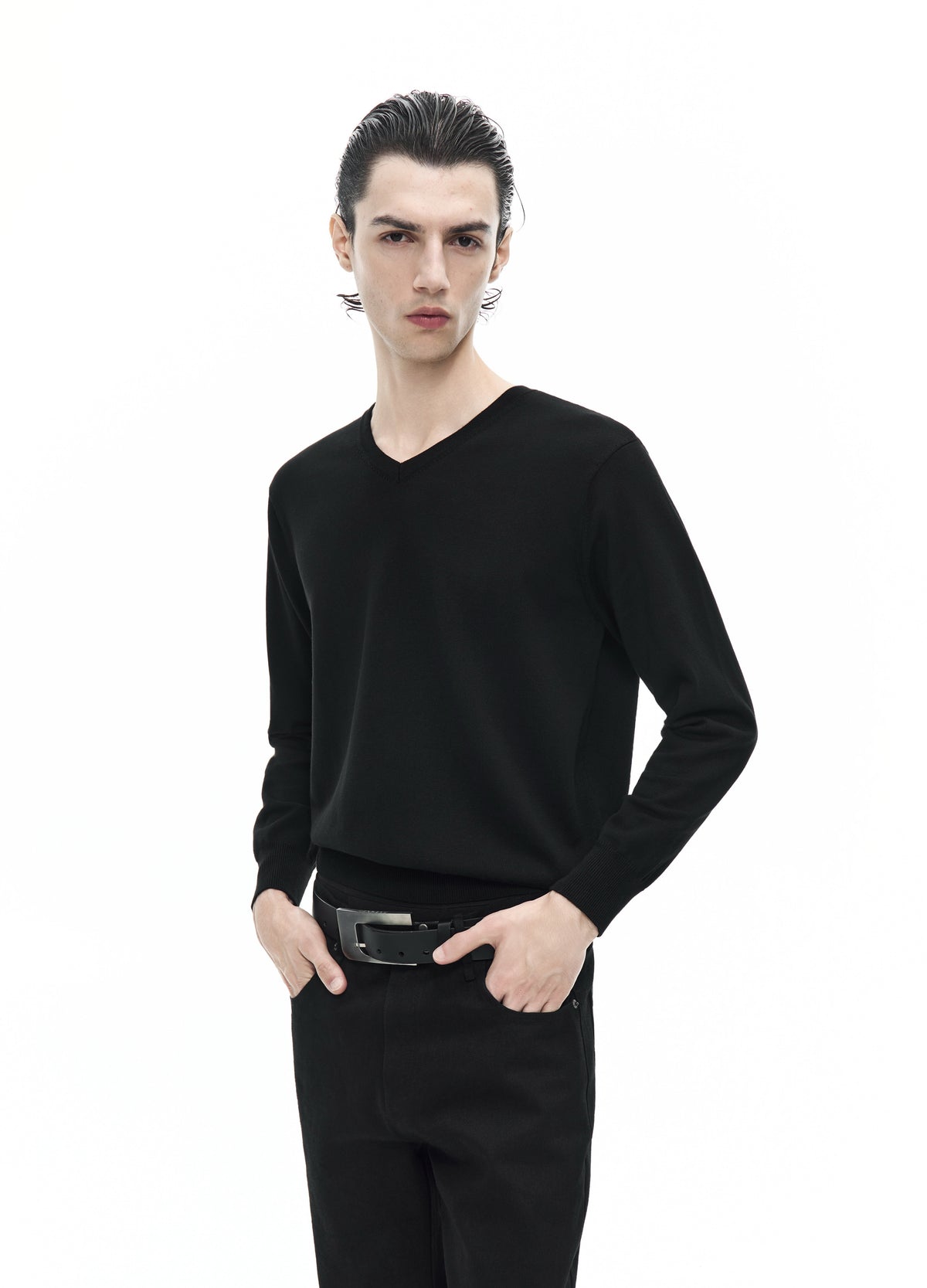 Closer front view of the black V-neck top, showing the neckline, long sleeves and softly gathered fabric above the belt.