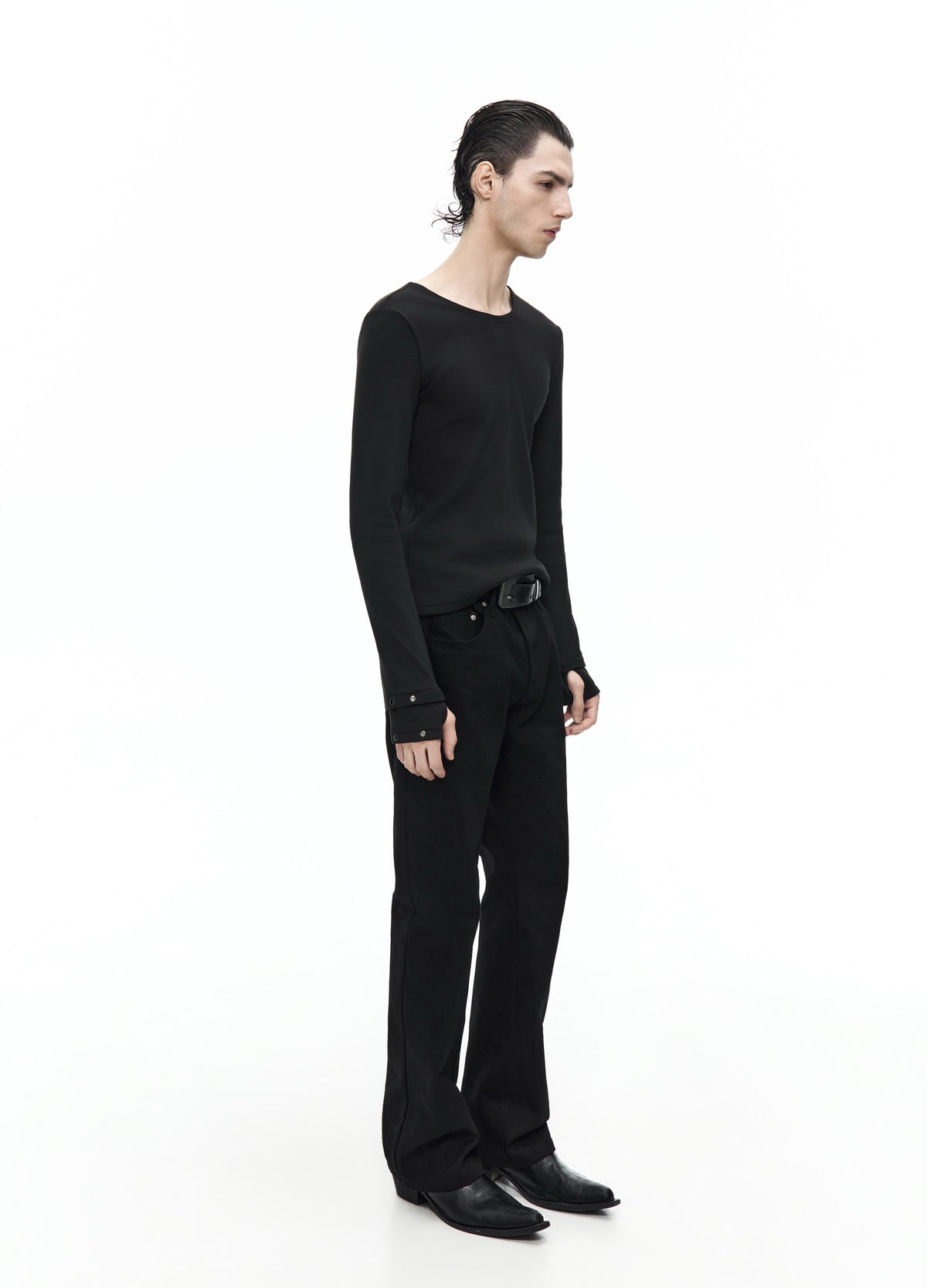Side view of the fitted black long-sleeve top, showing the slim silhouette and cuffs extending over the hands.
