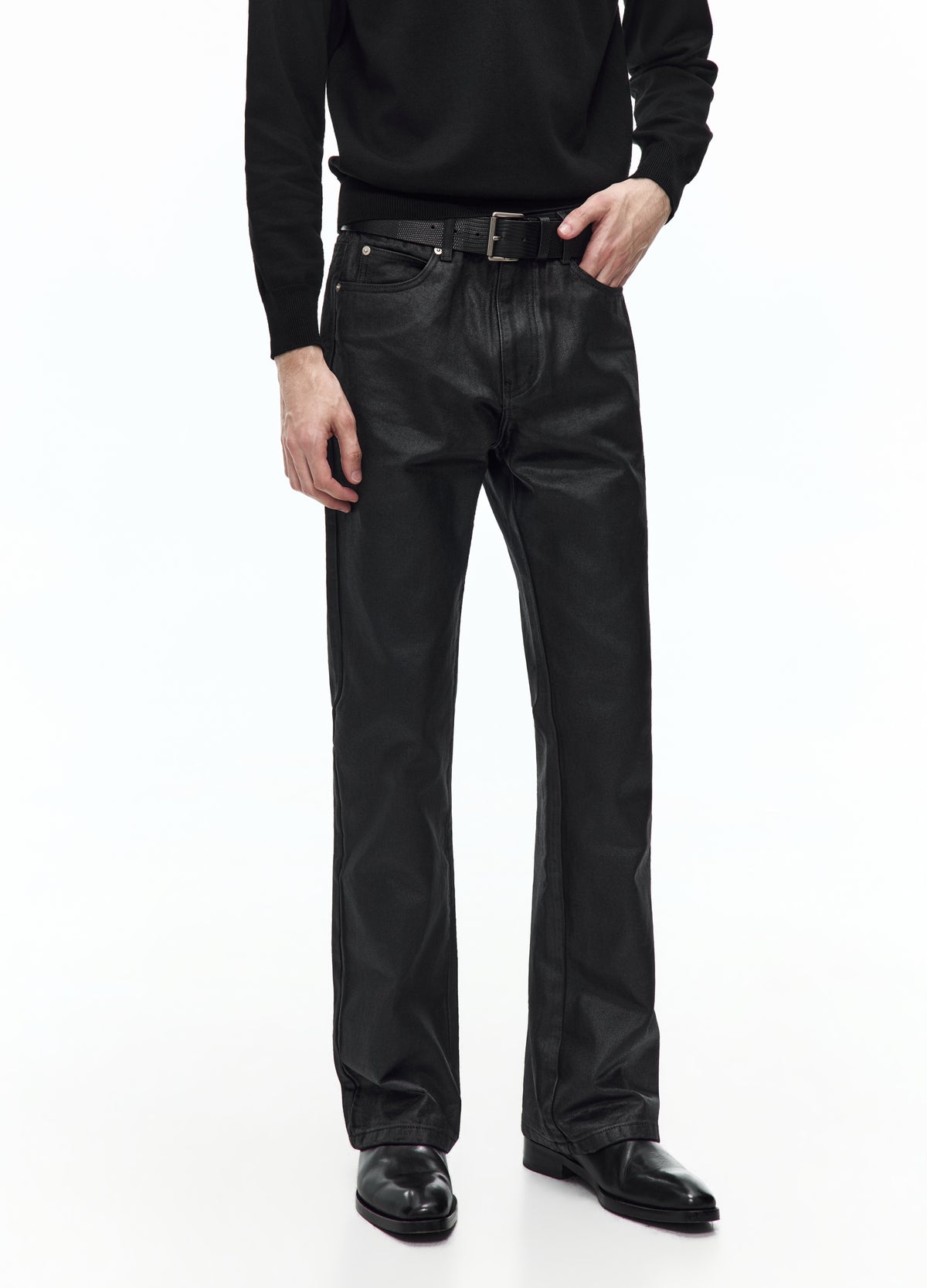 Alternate front view of the glossy black trousers, showing the belt, front pockets and long legs opening slightly over the shoes.