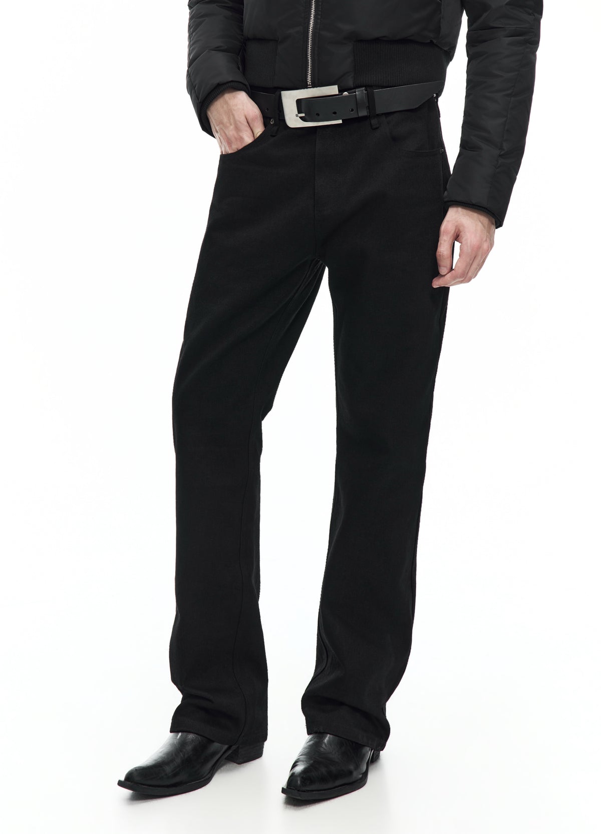 Three-quarter view of straight black jeans from the waist to the shoes, with one hand in a front pocket.