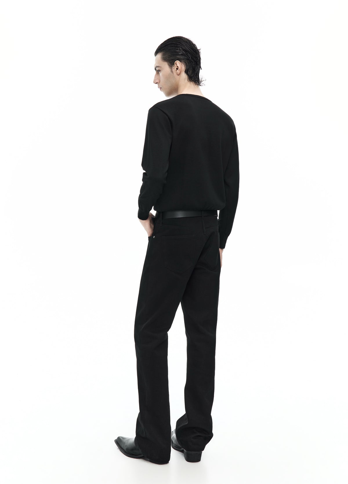 Rear three-quarter view of the black long-sleeve top, showing its plain back and hem above straight black trousers.