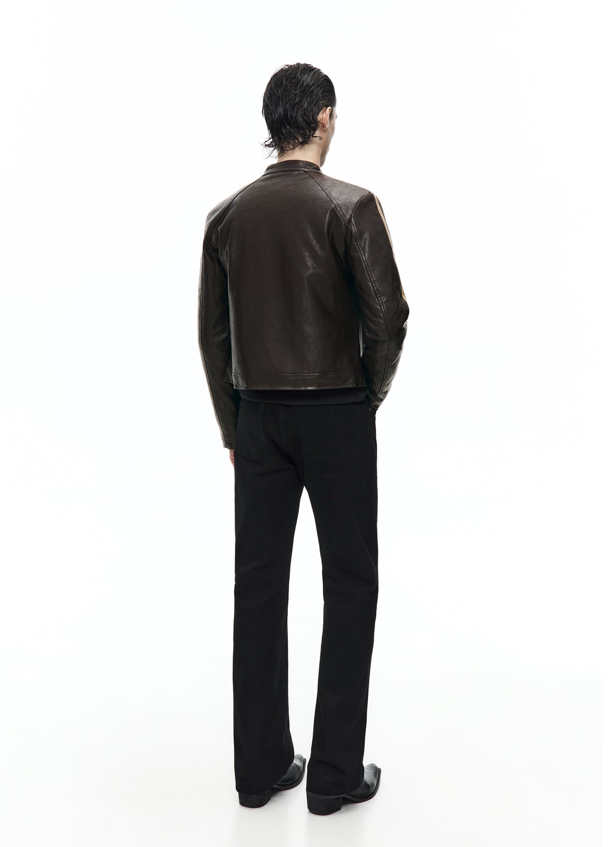 Rear view of the dark brown jacket, showing the plain back, short hem and pale shoulder stripes above black trousers.