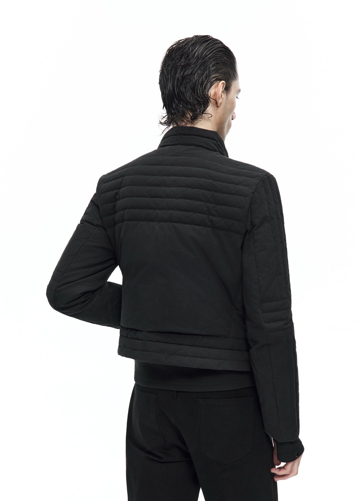 Closer rear view of the black quilted jacket, showing horizontal channels across the upper back and quilting near the hem.