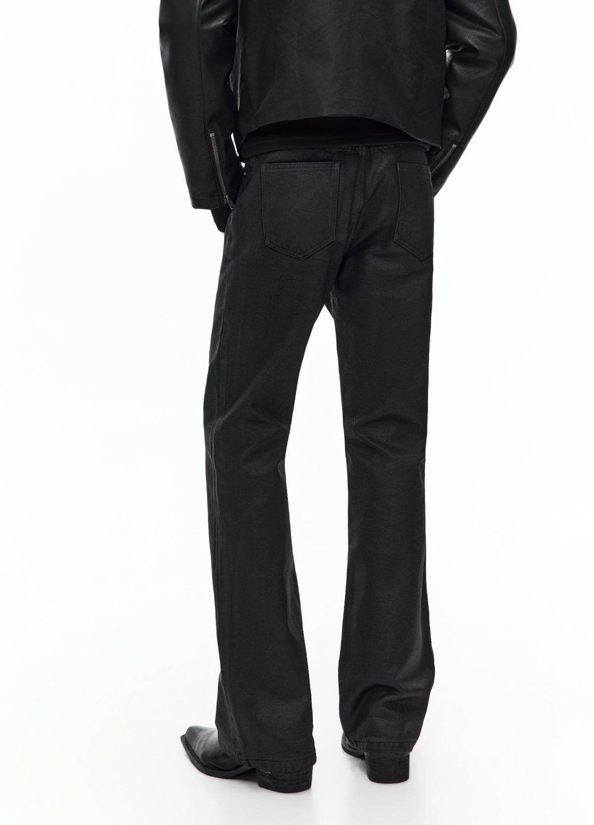 Rear view of the glossy black trousers from the waist to the shoes, showing two back pockets and slightly flared hems.
