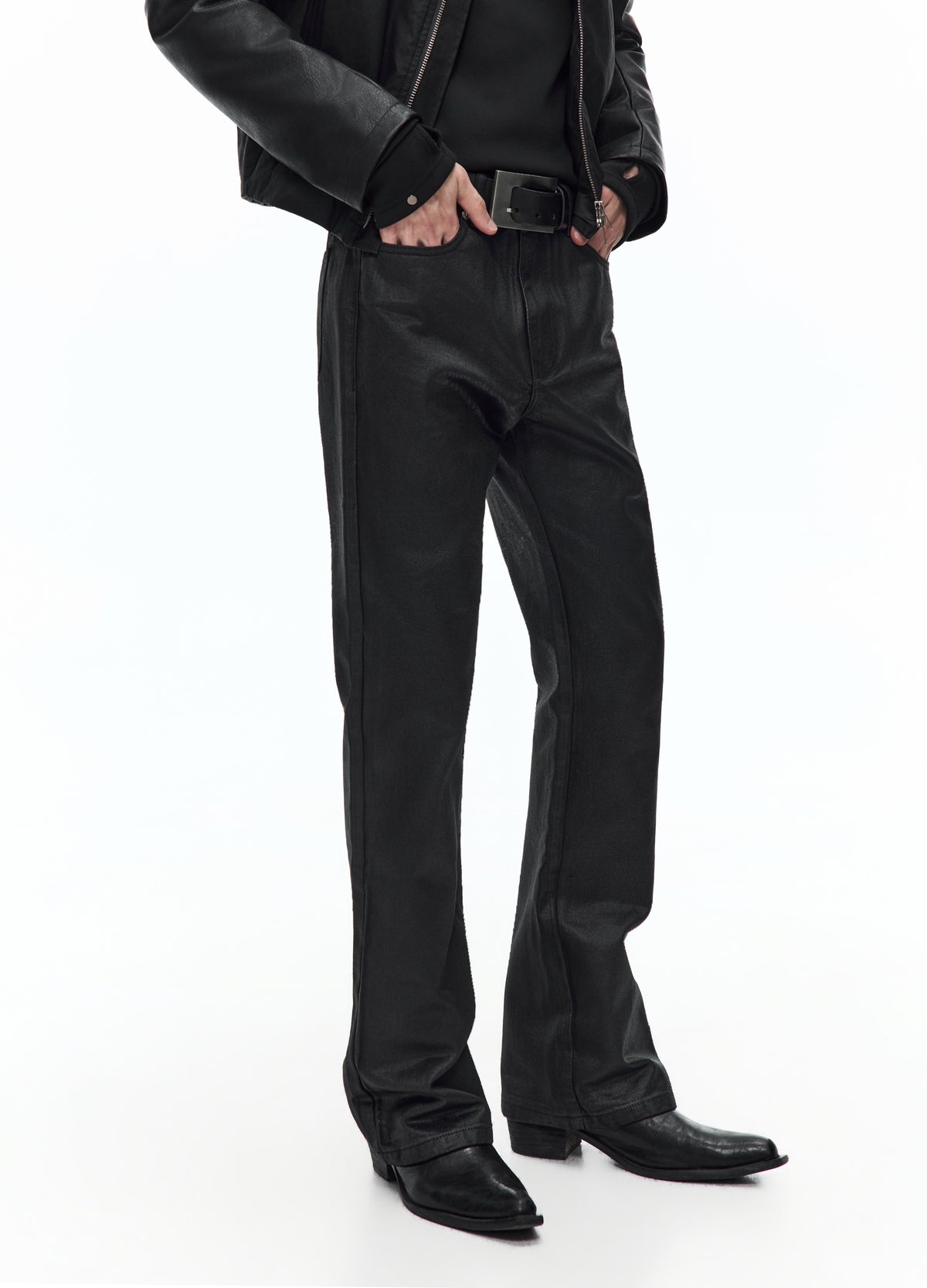 Three-quarter view of the glossy black trousers from the waist to the shoes, showing the front crease lines and flared hems.