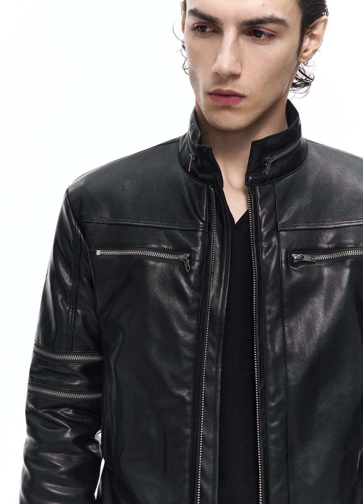 Close view of the black jacket, showing the stand collar, two horizontal chest zips, central zip and a zip across the upper sleeve.