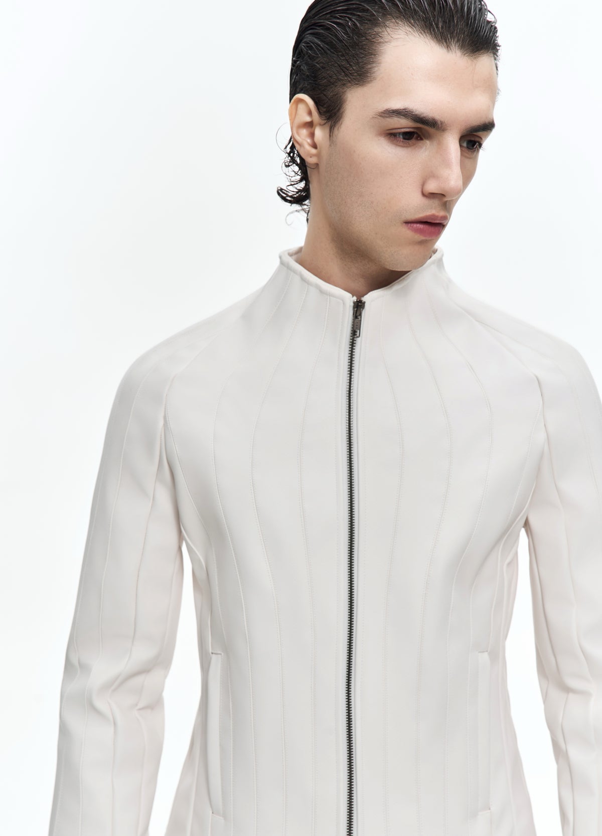 Close front view of the off-white jacket, showing the stand collar, central dark zip and curved stitched panels.