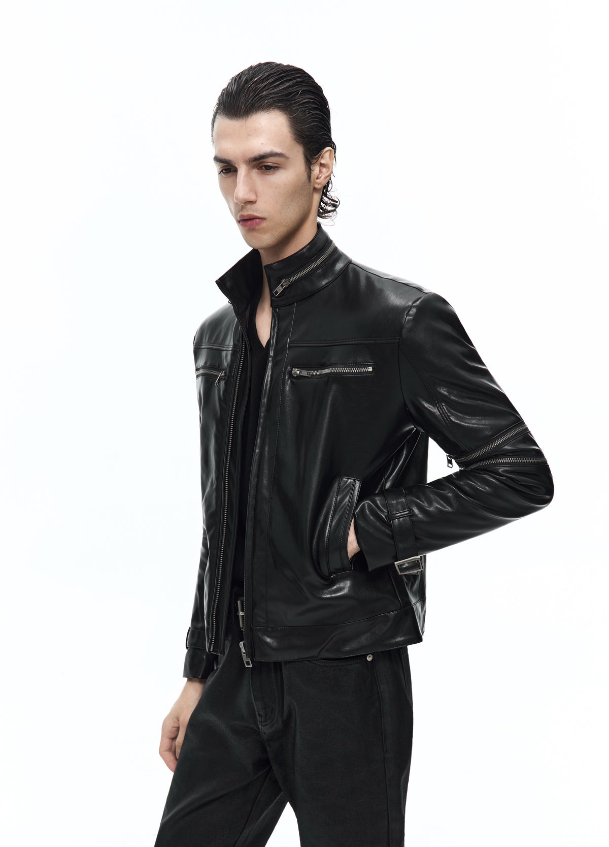 Three-quarter view of the black jacket, showing the stand collar, chest zip, sleeve zip and one hand in a side pocket.