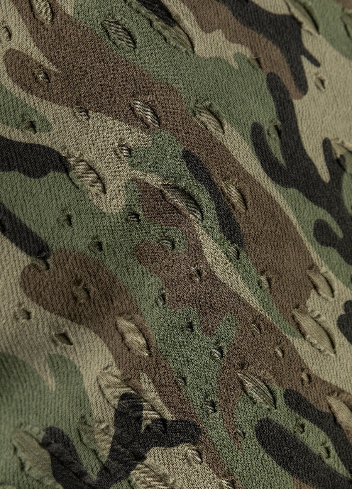 Distressed camouflage fabric with small openings.