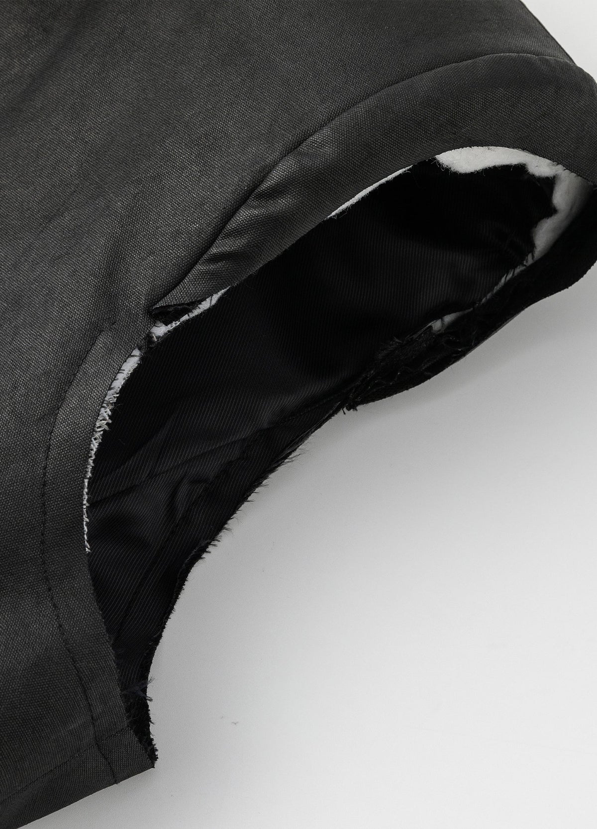 Raw armhole edge and exposed inner layer.