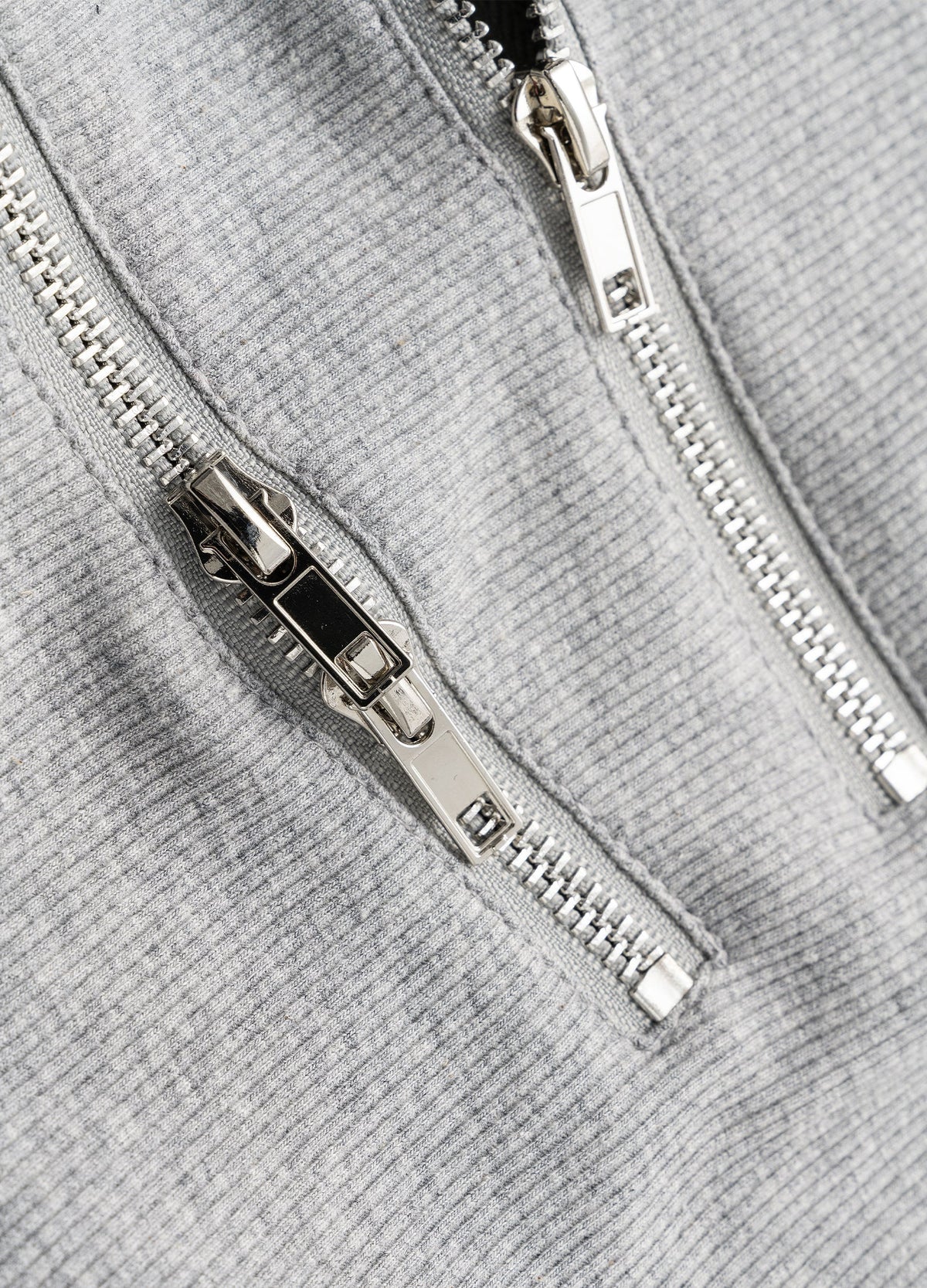 Metal zipper pulls and tracks on grey rib knit.